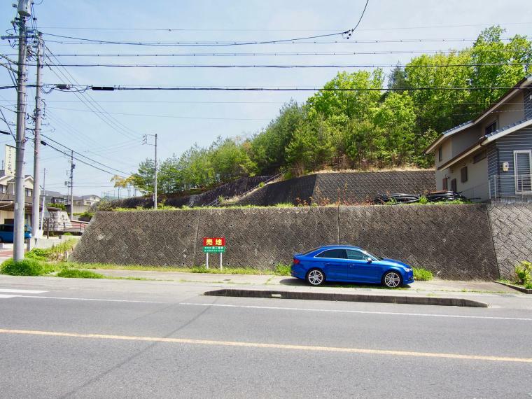 現況写真 北西側県道の向かいより全景。青い車の駐車部分は駐車スペースです