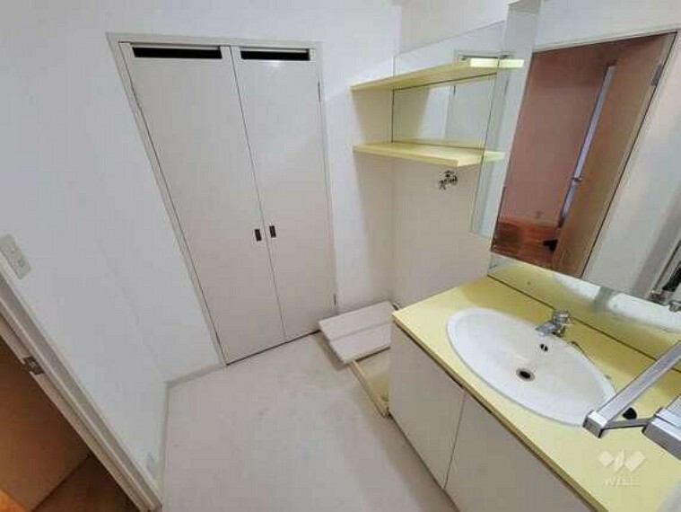 洗面所です。黄色の洗面台がおしゃれです。とびらの奥のスペースには電気温水器がセットされています。