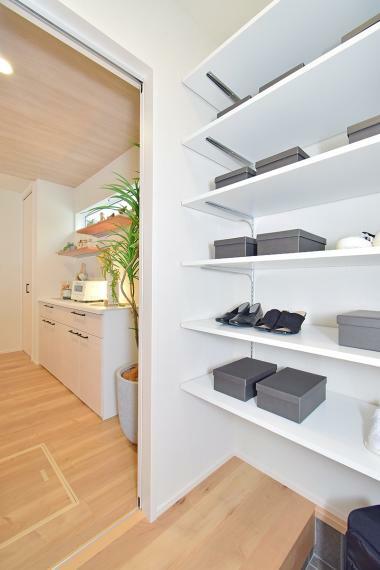 収納 玄関とキッチンをつなぐ便利な、可動棚のある収納スペース（9号地 モデルハウス）