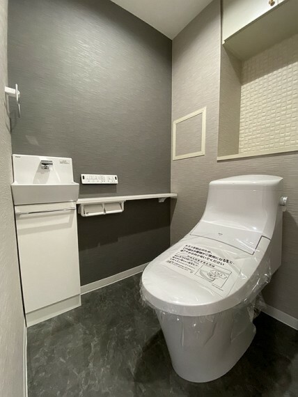 トイレ アクセントクロスを上手く取り入れ、落ち着きを感じる空間に。手洗い器があり、室内の清潔を保てます。