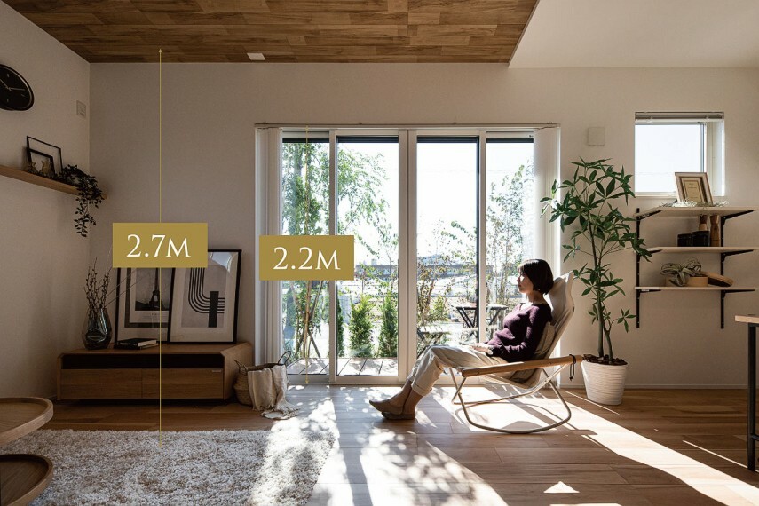 居間・リビング 【リビングの天井高は2.7m】  リビングダイニングのサッシ高や天井高は一般住宅と比べて高く設定し、明るさと開放感を作り出す工夫を採用。リビングの掃出しサッシ1箇所の高さを2.2mを確保したことで庭の風景や陽光を室内に採り込みます。