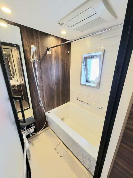 換気に最適な窓付き浴室。清潔感のあるシンプルなデザインの浴槽。浴室の壁は木目調パネルで高級感と落ち着いた雰囲気を演出しています。24時間換気、浴室乾燥機等、充実の機能が付いています