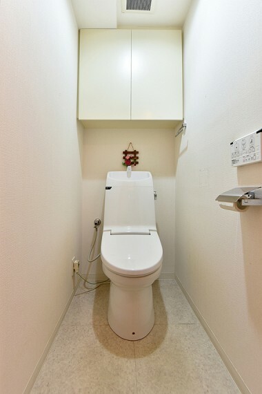 トイレ 温水洗浄機能付きのトイレには上部吊戸棚があり、掃除用具なども収納可能です。