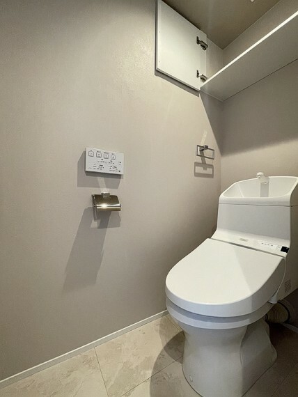 トイレ シックな雰囲気で落ち着きを感じる、温水洗浄便座付きのトイレです。トイレ用品の収納に便利な棚を設置。