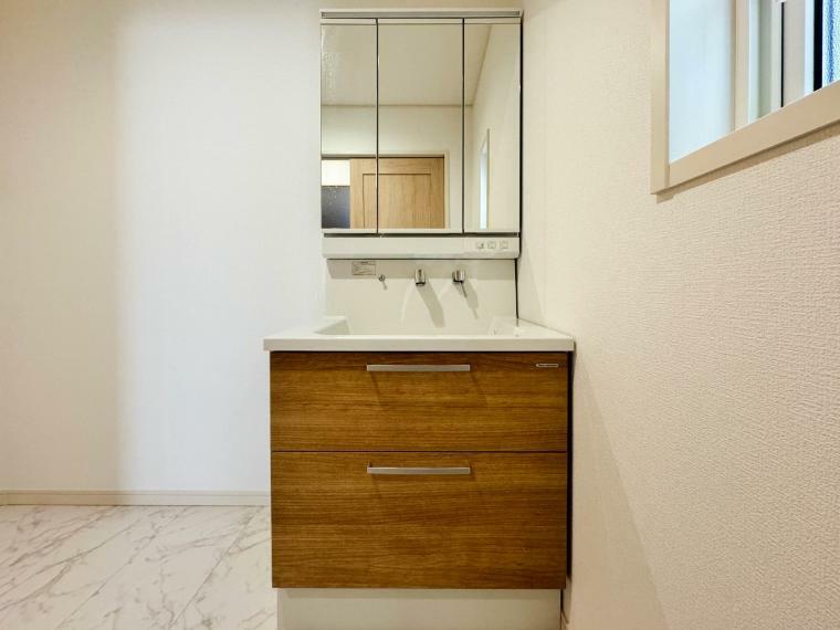 洗面化粧台 【Powder room】 （2号棟）大きく見やすい三面鏡で清潔感ある洗面台は、身だしなみチェックや肌のお手入れに最適です。何かと物が増える場所だからこそ、スッキリと見映えの良い空間に拵えました。