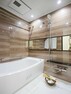 浴室 横長ミラーの効果で実際のサイズよりも広がりを感じるバスルームです。光沢感のある木目調のパネルが、より一層くつろぎと高級感を醸し出します。