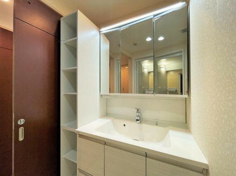洗面化粧台 三面鏡付きの洗面台の横は、タオルやお子様の部屋ぎなどの保管ができる棚があります。