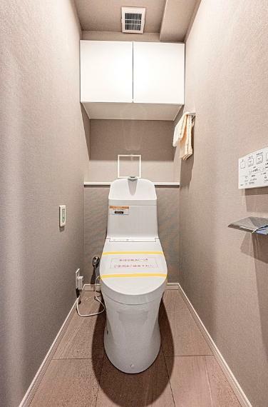 トイレには快適な温水洗浄便座付き。吊戸棚にはトイレまわりで使う物を収納できて便利です。