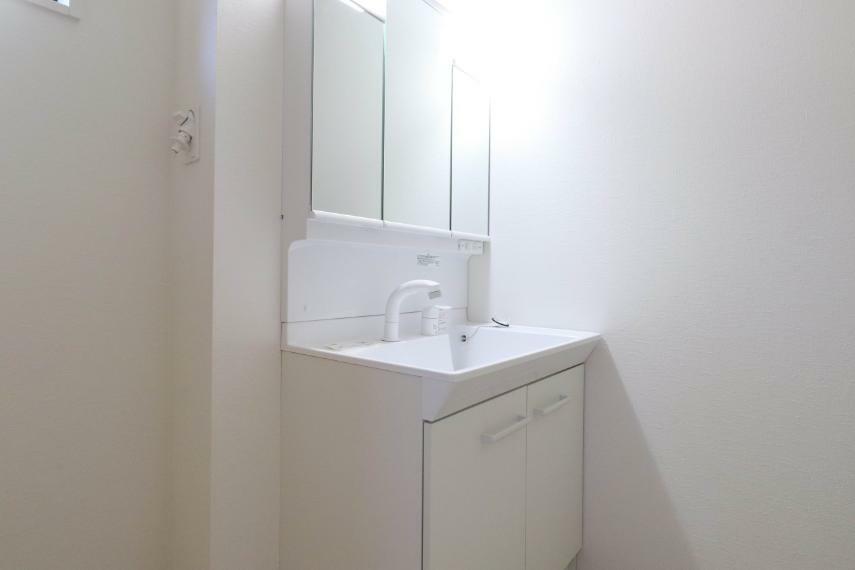 洗面化粧台 大きく見やすい三面鏡で清潔感ある洗面台は、身だしなみチェックや肌のお手入れに最適です。何かと物が増える場所だからこそ、スッキリと見映えの良い空間に拵えました。