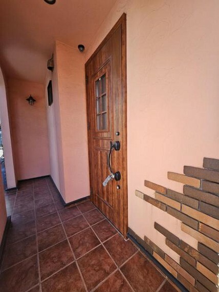 玄関 ピンクの外壁塗装とレンガのアクセント、木製のドアなどオシャレな外観です！