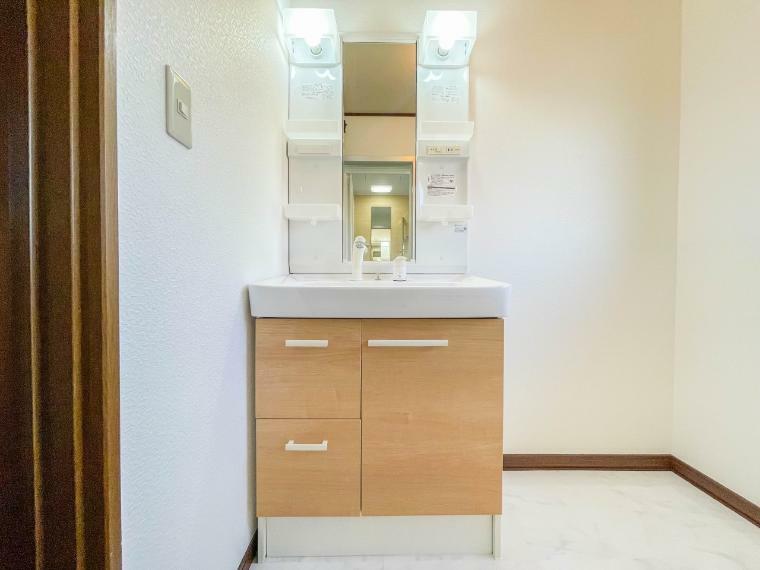 洗面化粧台 大きく見やすい三面鏡で清潔感ある洗面台は、身だしなみチェックや肌のお手入れに最適です。何かと物が増える場所だからこそ、スッキリと見映えの良い空間に拵えました。