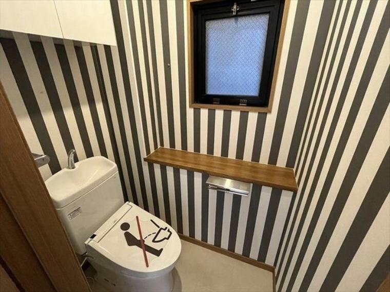 トイレ 2階トイレ:ポップな壁紙で個性的な個室。収納棚付きで、トイレットペーパーのストックも置いておけます 棚には芳香剤を置いたり小物を置くことができますね。（2024年3月11日撮影）