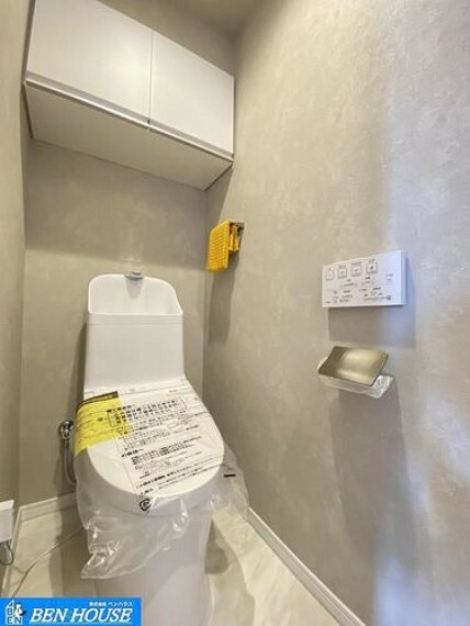 トイレ ・新規交換済のシャワー洗浄機能付のトイレ・清潔感が印象的な空間です・リモコンは壁掛けタイプでお手入れもしやすい設備です・吊戸棚の設置があり、トイレットペーパーやお掃除道具なども収納できます