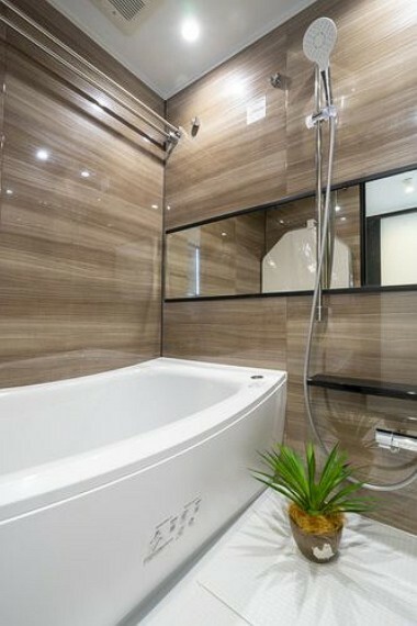 浴室 光沢のある木目調パネルが高級感を演出するバスルームです。ゆったりとしたバスタブで上質なリラックスタイムをお楽しみいただけます。