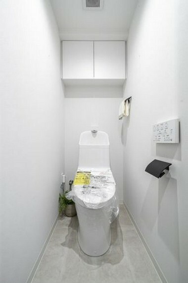トイレ 清潔感溢れるホワイト基調のレストルームです。上部吊戸棚収納が備わっているため、掃除用品やペーパー類もすっきりと収納可能です。
