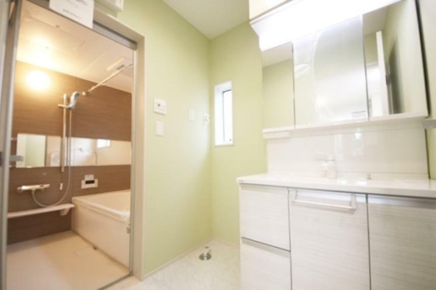 洗面化粧台 淡い萌黄色の壁紙が柔らかな印象の洗面室、三面鏡付きの洗面台つき