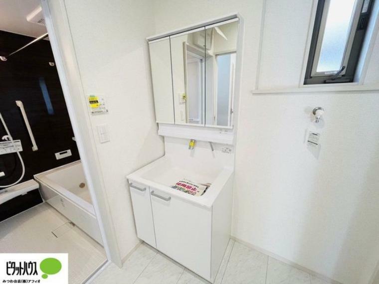 施工例写真:シャワー付き三面鏡洗面台。上部にも収納スペースがあり、小物がスッキリ片付きます