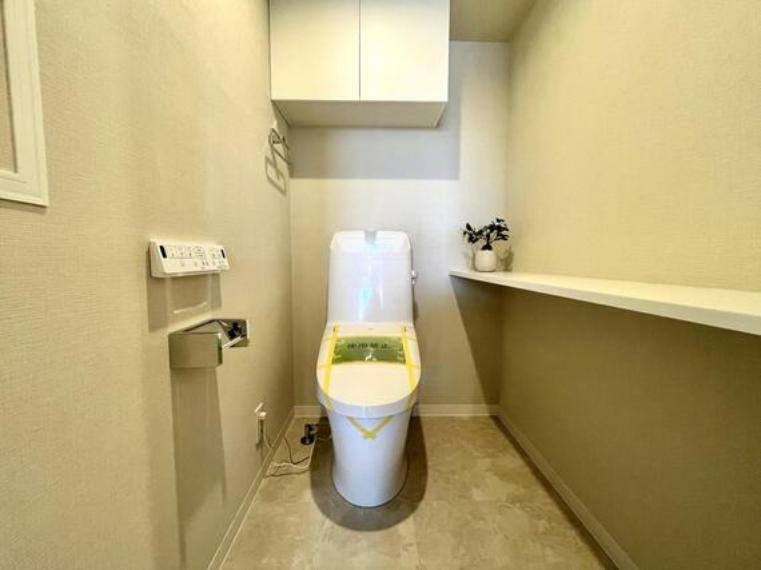 トイレ 毎日快適に使える温水洗浄便座付き。掃除用具などを隠して仕舞える吊戸棚が造作されています。