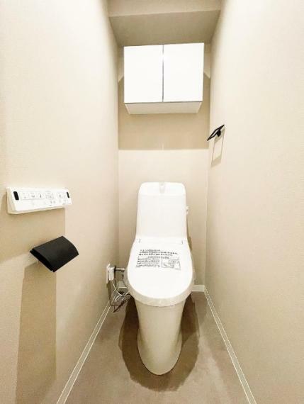 トイレ ウォシュレット一体型のトイレ。吊戸棚は、トイレットペーパーや掃除用具などが収納できて便利です。