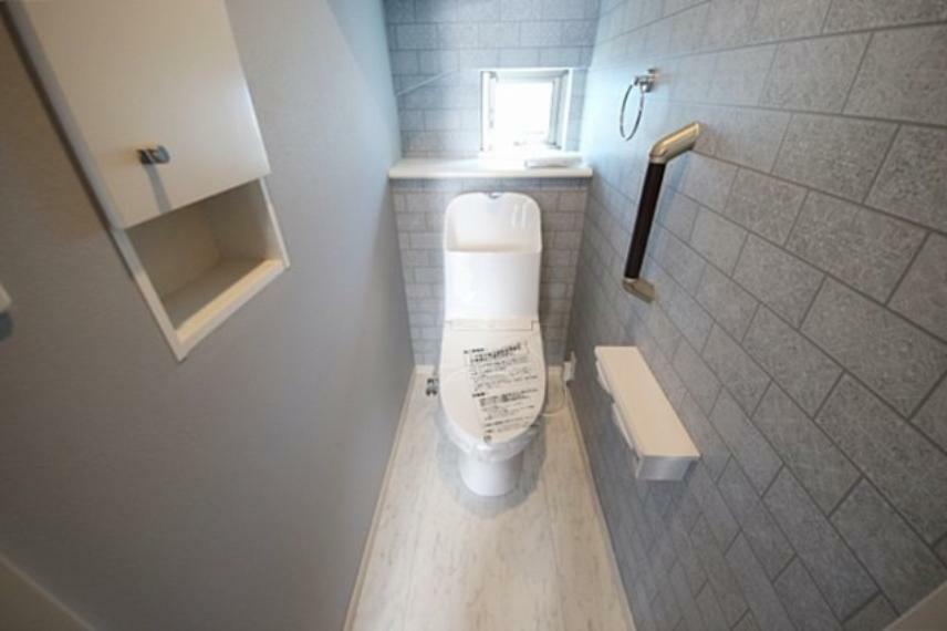 トイレ タイル調クロスが個性的なトイレ、手すり付きで安心して利用できるのも嬉しいポイント