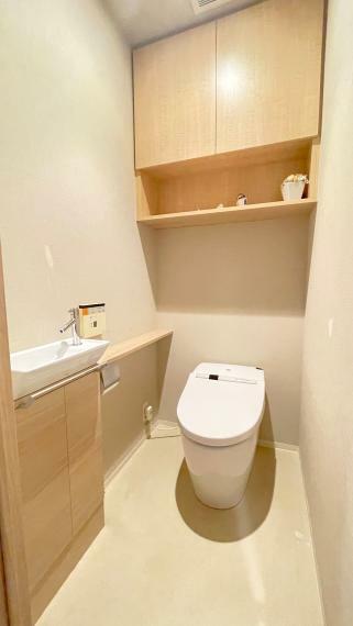 手洗いカウンター付きタンクレスウォシュレットトイレ。小物類やストックなどもしまえる収納付き。室内（2024年4月）撮影