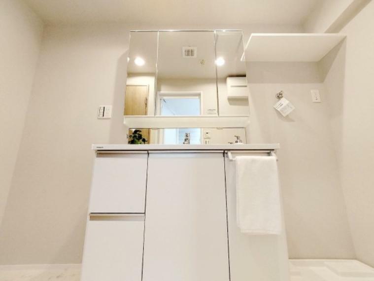洗面化粧台 シンプルにまとめた室内はホテルライクな空間を創造しております。身だしなみのチェックがしやすい大きな鏡、鏡の裏には収納がたっぷり。棚もあるのでスッキリとした空間をお作りいただけます。