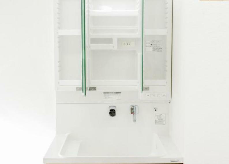 洗面化粧台 【リフォーム済】洗面台の鏡は三面鏡タイプで内部が収納棚になっています。収納の内部にコンセントがあるので電動歯ブラシや電気シェーバーなどは充電したまま収納することができます。