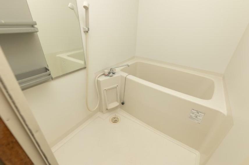 浴室 白色で統一されたきれいで清潔感のある浴室。シャワー、棚、鏡がついており、湯はり機能があります。浴槽につかれば一日の疲れも吹き飛びそうです。窓はありませんが、換気扇があるので湿気がこもりにくいですよ。