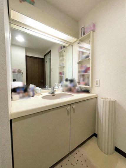 洗面室　大きな一面鏡の洗面化粧台の写真です。コスメやヘアケアグッズなどをしまえる収納棚がございます。
