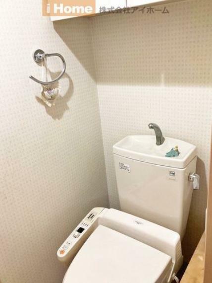 トイレ 備え付けの収納棚や温水洗浄便座付きのトイレ。