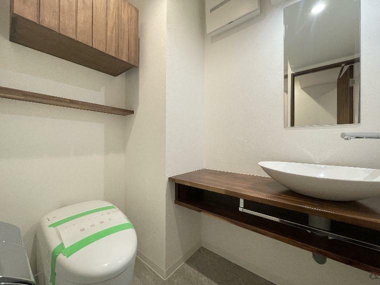 タンクレスですっきりとしたデザインのウォシュレット付きトイレです。室内は天然無垢材の温もりを感じる落ち着いた上質な空間です。吊戸棚も設置されており、トイレットペーパーなどの消耗品の収納ができます。ミラー付の便利な専用手洗いスペースも付いています。【弊社施工事例】
