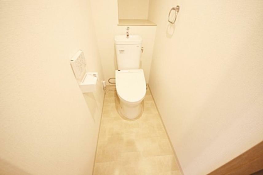 トイレ 白を基調とした清潔感あるトイレ、後ろに設けた棚は物を取り出しやすいオープンタイプ