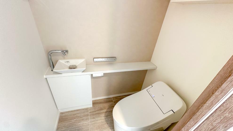 トイレ 手洗いカウンター付きウォシュレットトイレ。小物類やストックなどもしまえる収納付き。室内（2024年4月）撮影