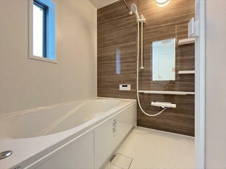 浴室 木目調の壁が落ち着いた印象を与えてくれる浴室です。棚や小物を置くスペースもついているので、シャンプーなどを置くのに便利ですね。（2024年3月28日撮影）