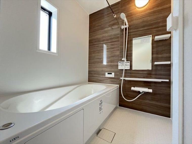 浴室 木目調の壁が落ち着いた印象を与えてくれる浴室です。棚や小物を置くスペースもついているので、シャンプーなどを置くのに便利ですね。（2024年4月25日撮影）